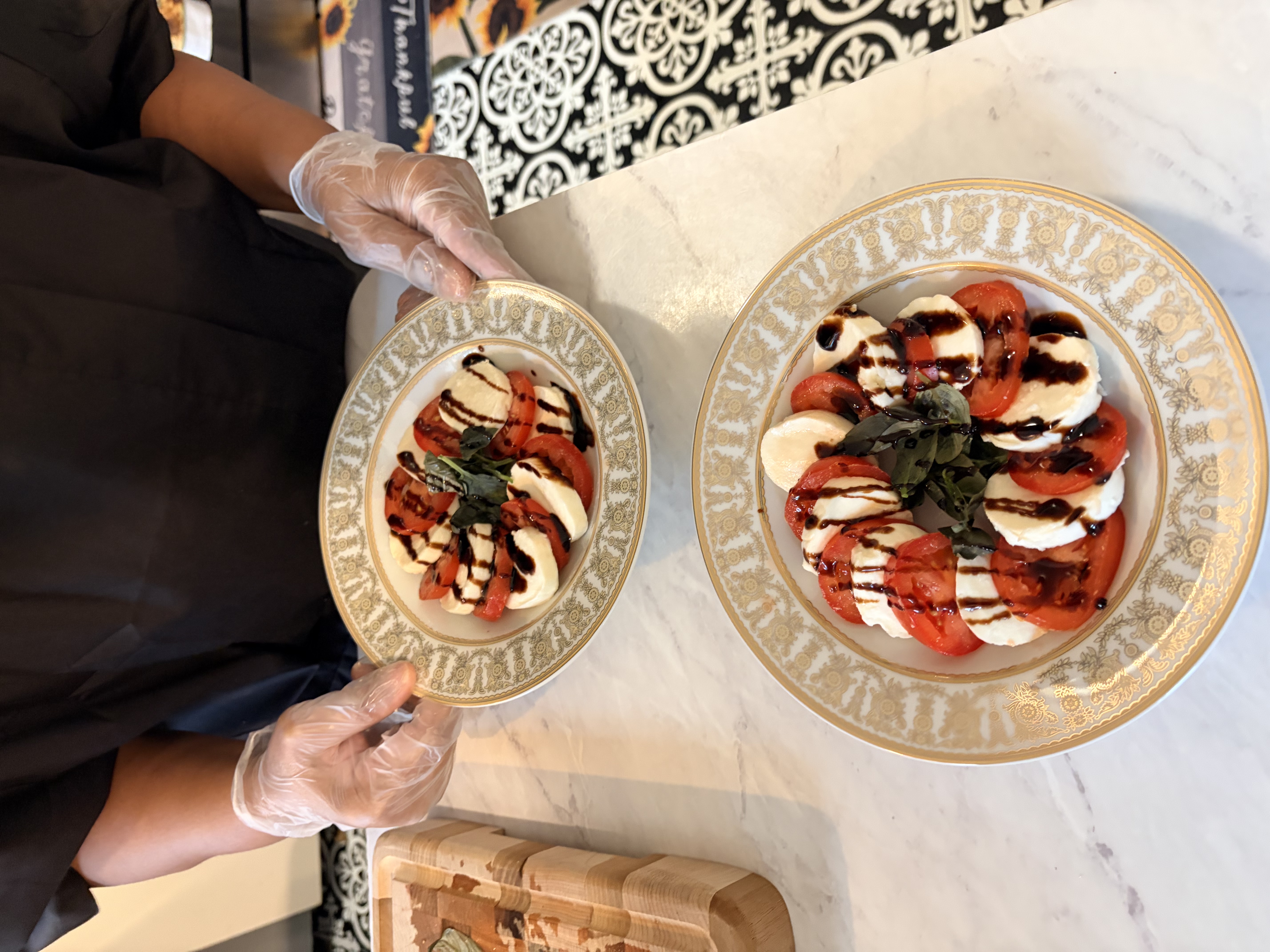 Caprese salad plated on gold-rimmed china for two