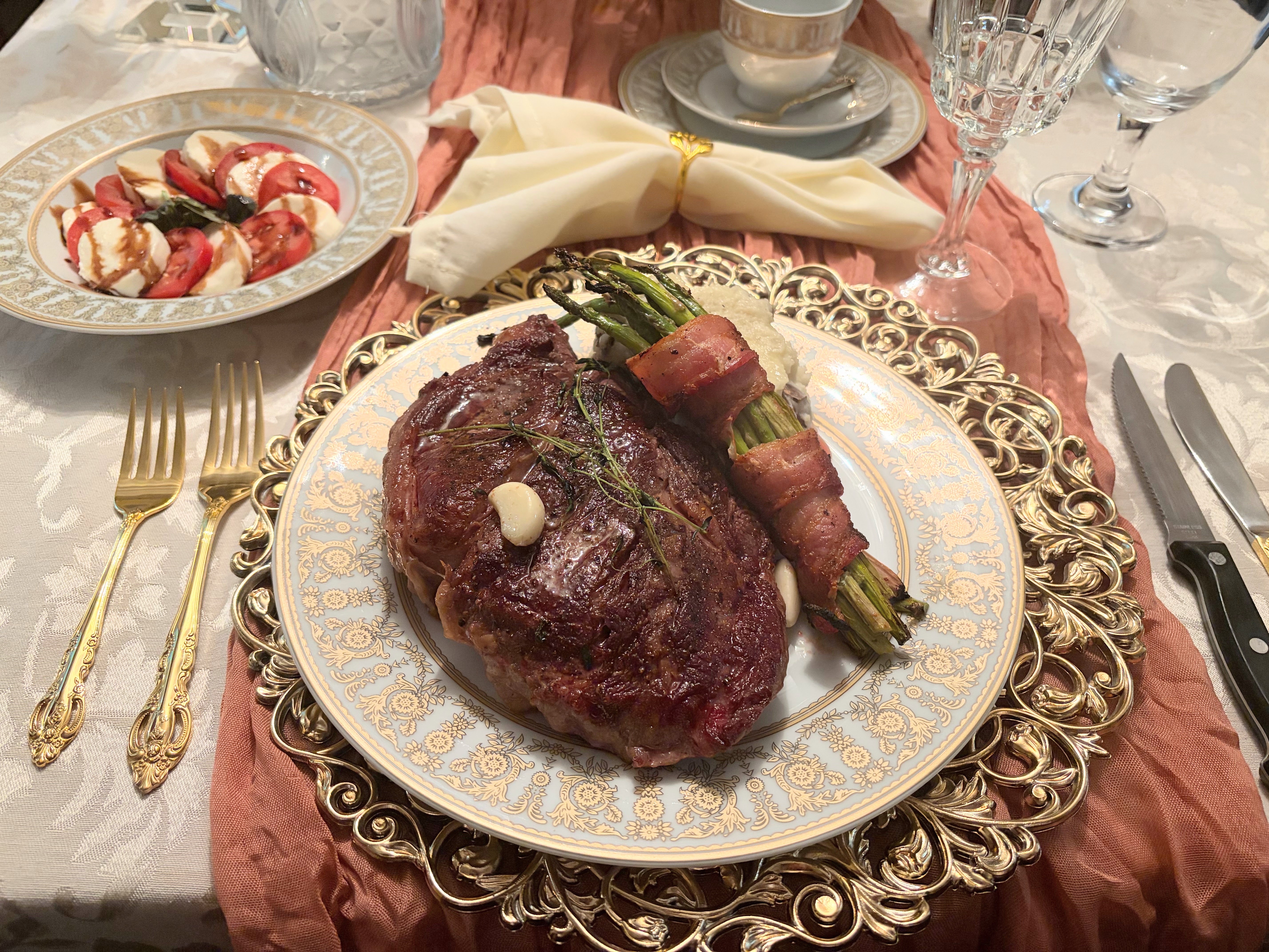 Seared steak with bacon-wrapped asparagus on gold-rimmed china