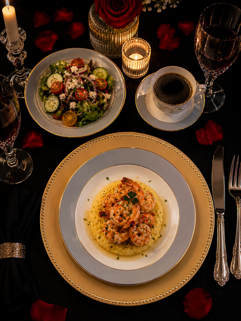 Intimate table for two with shrimp and grits, salad, and candlelight
